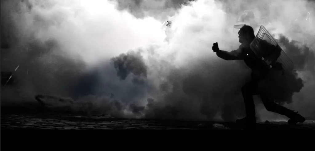 A black and white branded image of a man running through smoke,